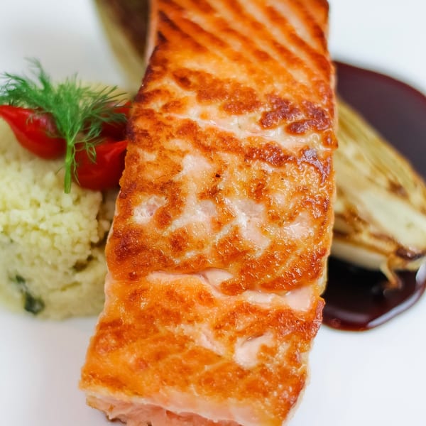 Waypoint Seafood & Grill's pan-seared salmon with couscous, cherry tomatoes, dill, and a dark sauce.