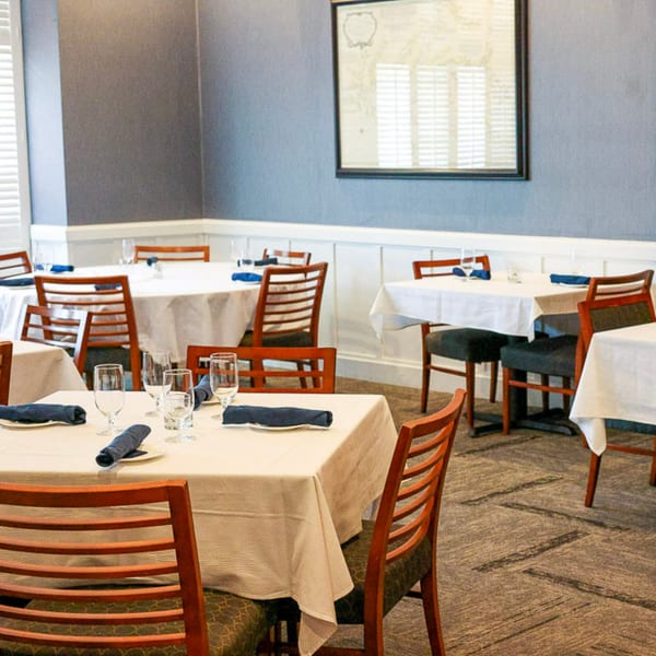 Waypoint Seafood & Grill dining room with set tables, wooden chairs, and blue walls.