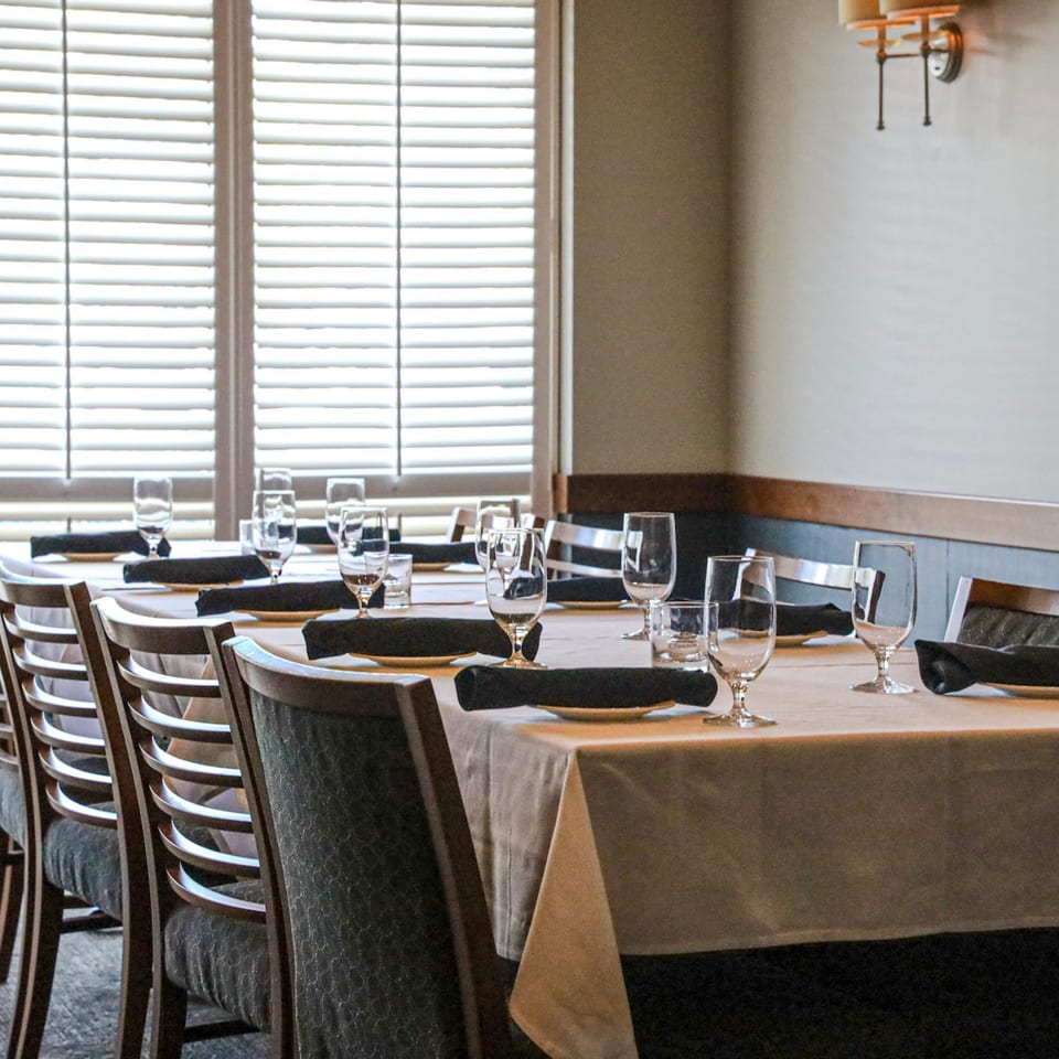 Waypoint Seafood & Grill dining room with set tables, chairs, and window blinds.