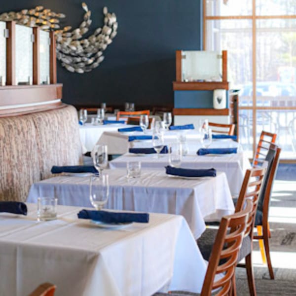 Waypoint Seafood & Grill dining room with set tables, blue napkins, and a fish art installation.